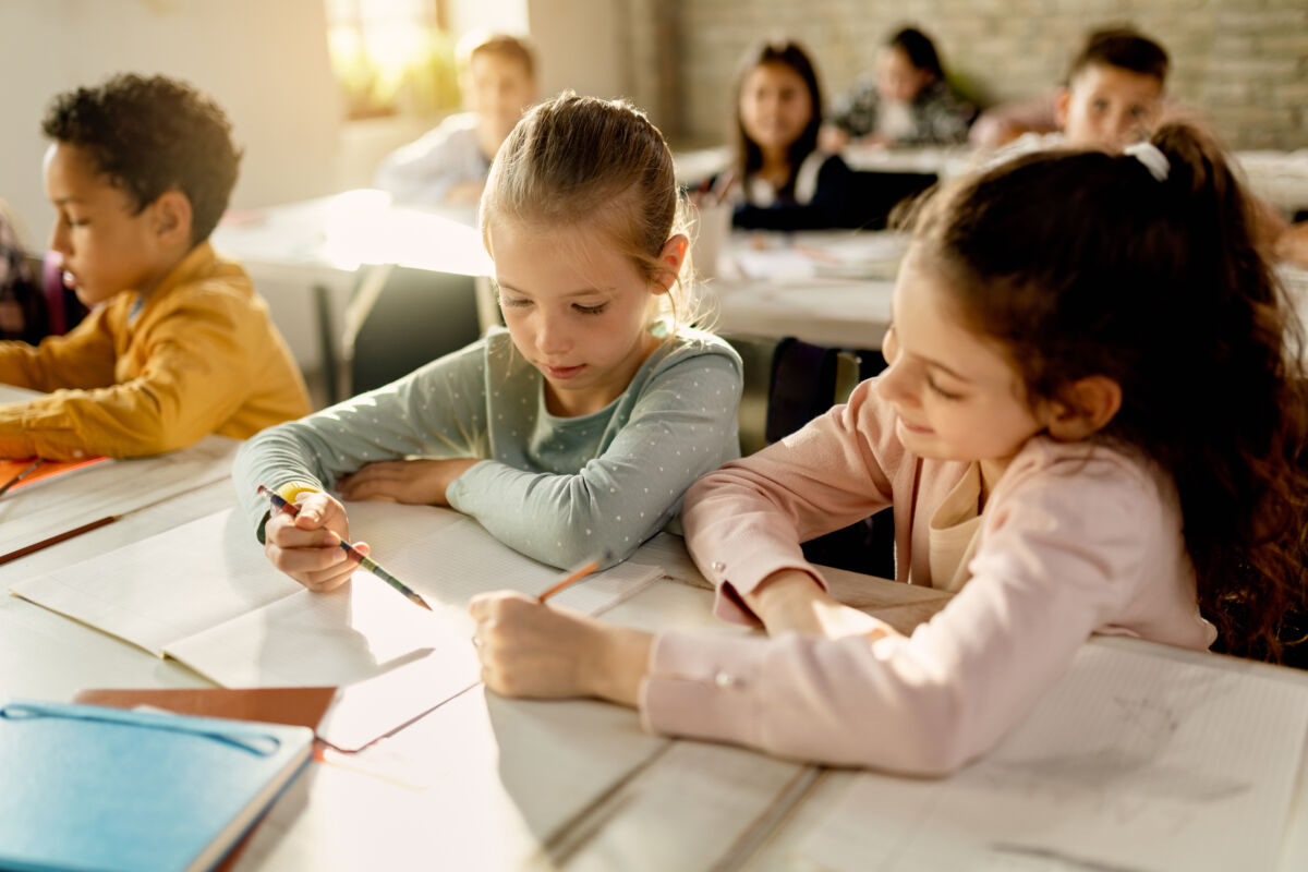 Two schoolgirls working together on a assignment in the classroo